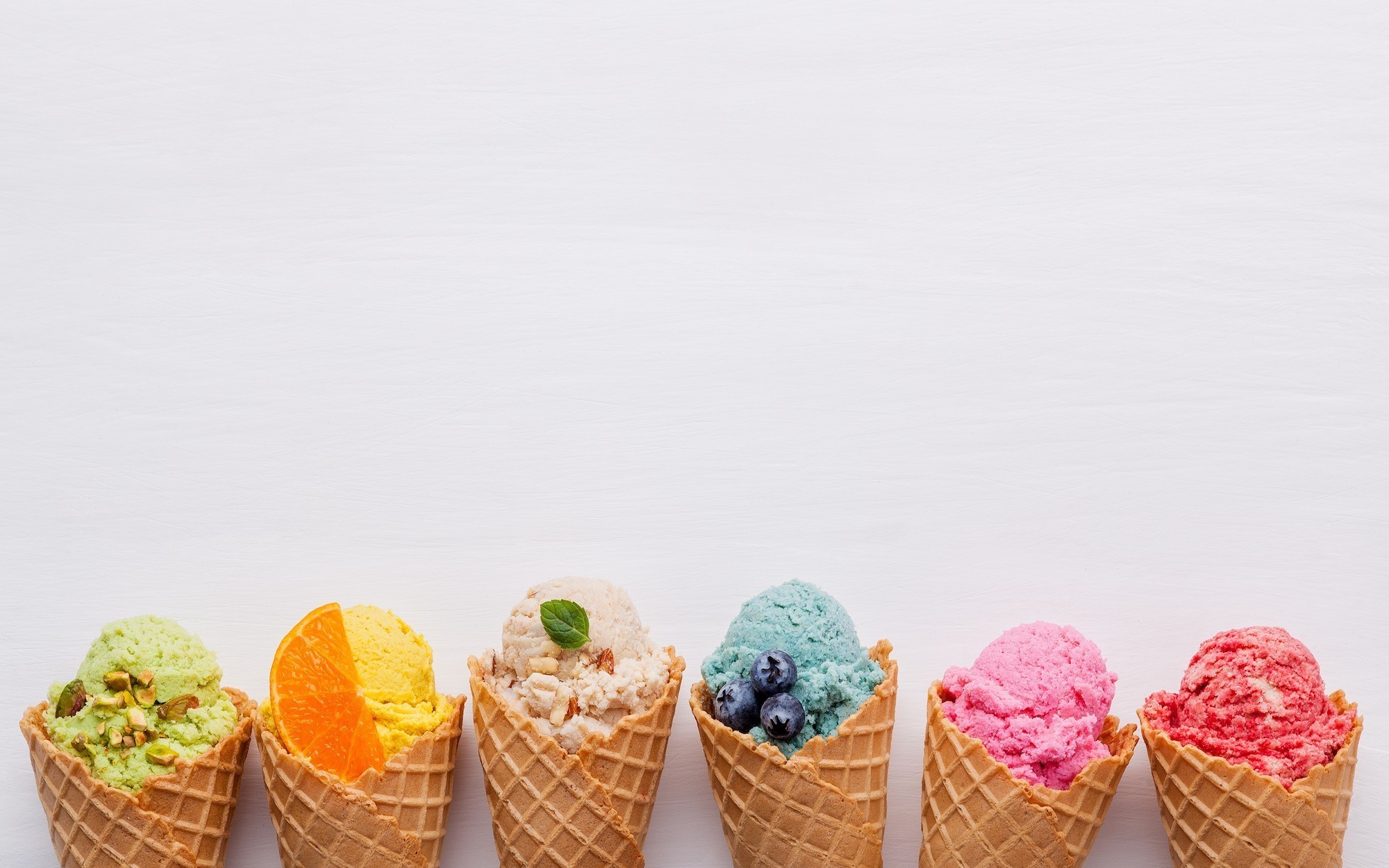 Shipping Perishables and Frozen Food: How to Get It Right Various of ice cream flavor in cones blueberry ,strawberry ,pistachio ,almond ,orange and cherry setup on white wooden background . Summer and Sweet menu concept.